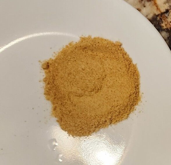 Fine-ground hot pepper powder on a plate after grinding dried peppers.