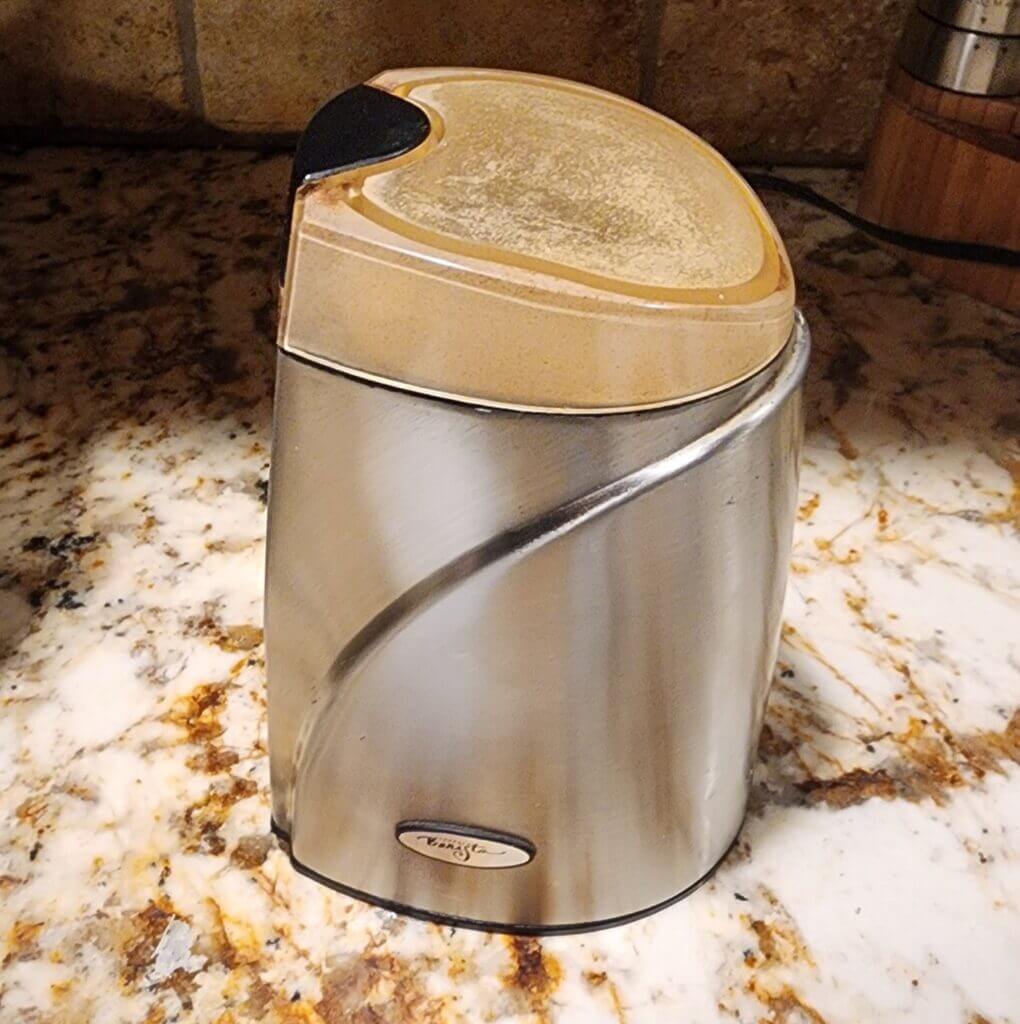 Stainless steel spice grinder turning dried hot peppers into fine powder.