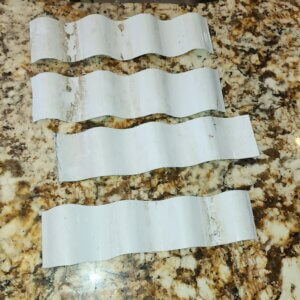 Strips of corrugated plastic roofing cut to size and laid out before heat flattening