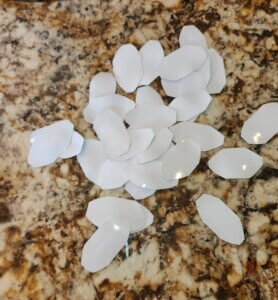 Rounded tabs cut from flattened plastic roofing with trimmed edges to prevent puncturing plastic sheeting